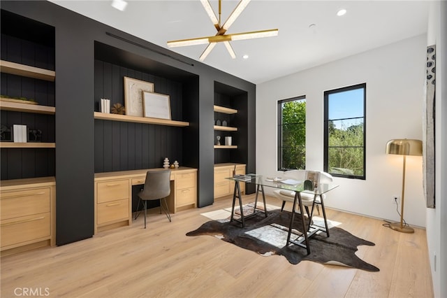 office area with built in shelves, light hardwood / wood-style flooring, and built in desk