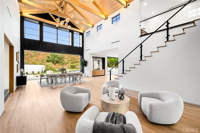 interior space with beam ceiling, high vaulted ceiling, wooden ceiling, and light wood-type flooring