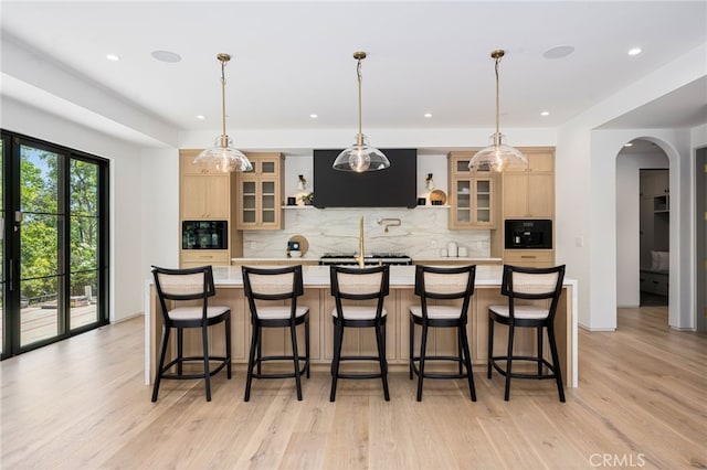 kitchen featuring light brown cabinets, a spacious island, light wood-type flooring, and ventilation hood