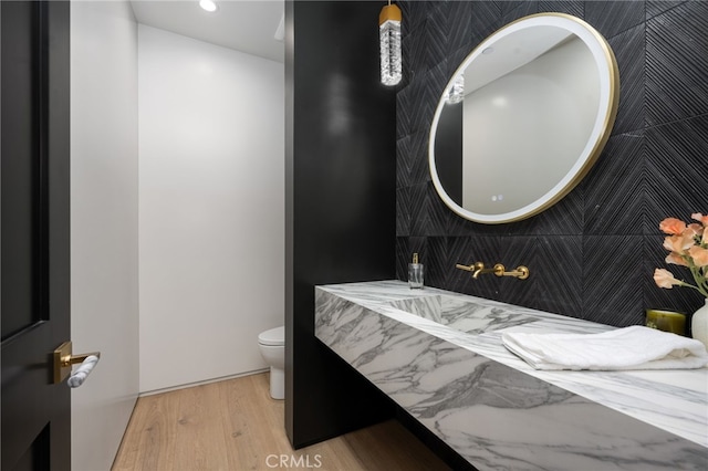 bathroom featuring wood-type flooring, tile walls, and toilet