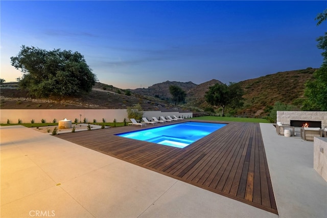 pool at dusk featuring a mountain view and a patio area