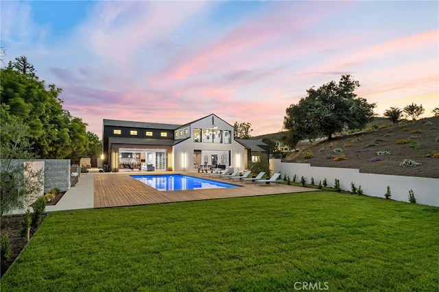 pool at dusk with a lawn and a patio