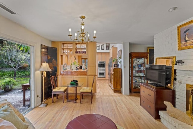 living room featuring a fireplace, a notable chandelier, and light wood-type flooring