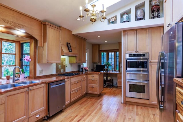 kitchen featuring plenty of natural light, stainless steel appliances, vaulted ceiling, and light wood-type flooring