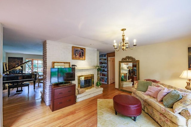 living room with light hardwood / wood-style floors, a fireplace, and an inviting chandelier