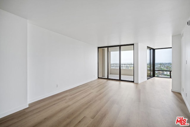 spare room with light wood-type flooring and floor to ceiling windows