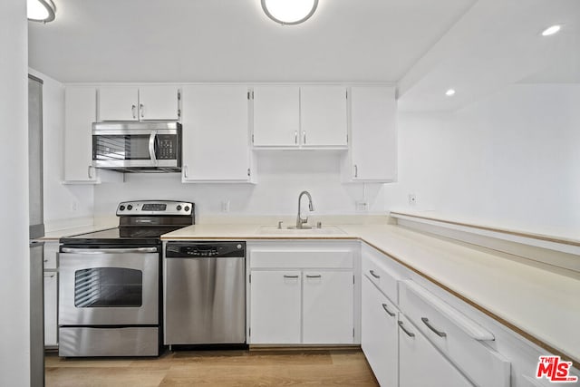 kitchen featuring light hardwood / wood-style flooring, white cabinets, appliances with stainless steel finishes, and sink