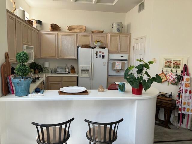 kitchen with a kitchen breakfast bar, kitchen peninsula, and white appliances