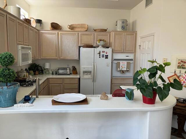 kitchen featuring kitchen peninsula, a breakfast bar, and white appliances