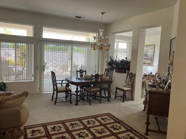 carpeted dining area featuring plenty of natural light and a chandelier