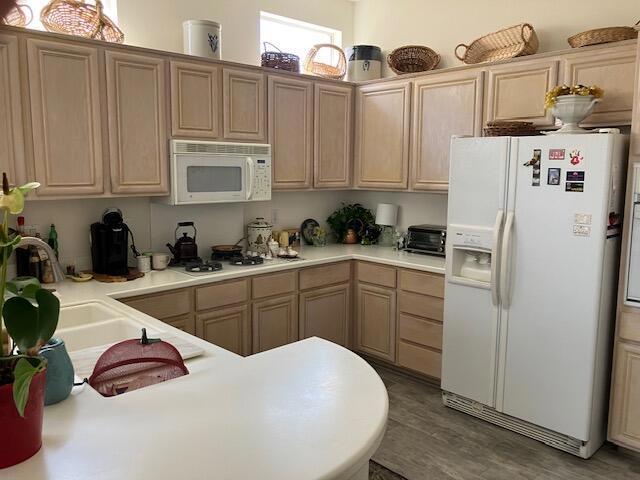 kitchen featuring light brown cabinets, wood-type flooring, sink, and white appliances