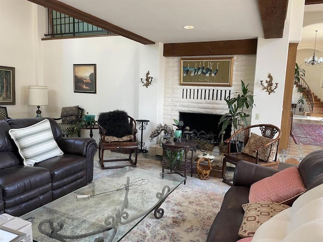 living room featuring beam ceiling, a brick fireplace, and a notable chandelier