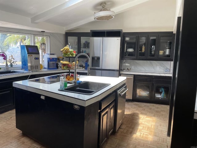 kitchen featuring stainless steel appliances, decorative backsplash, a center island with sink, and sink