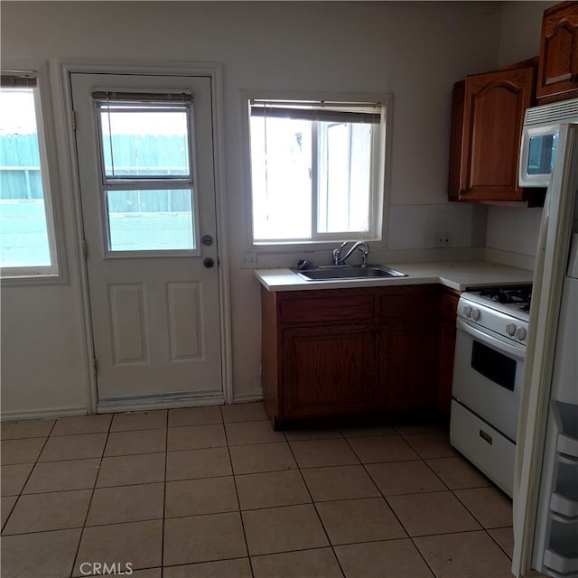 kitchen with white appliances, a healthy amount of sunlight, sink, and light tile patterned flooring