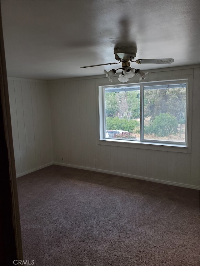 spare room with wooden walls, carpet floors, and ceiling fan