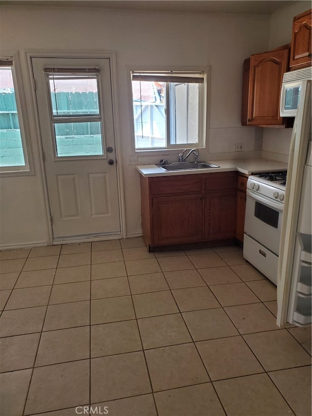 kitchen with sink, light tile patterned floors, and white appliances