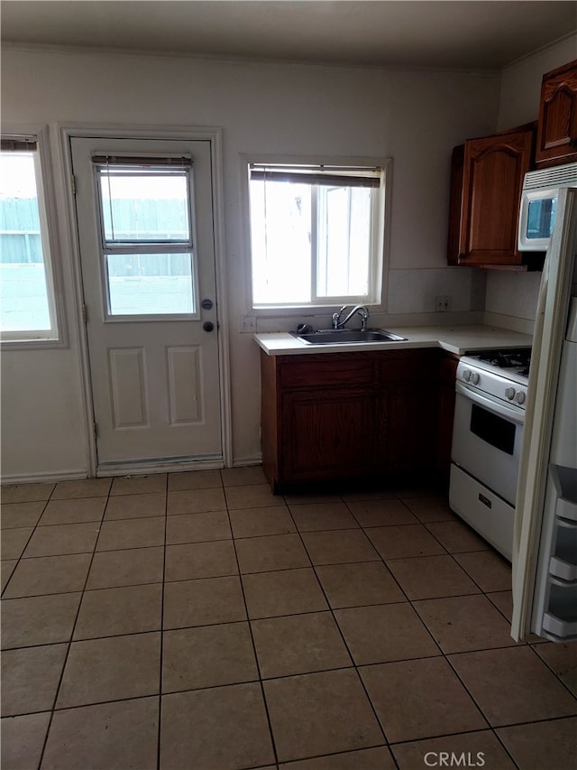 kitchen with white appliances, light tile patterned floors, sink, and plenty of natural light