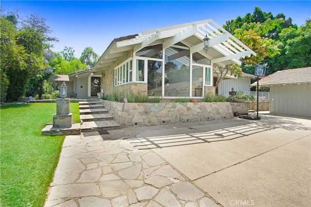 rear view of house featuring a pergola, a lawn, and a patio area