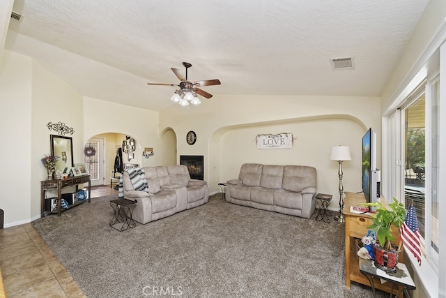 tiled living room featuring ceiling fan, a textured ceiling, and lofted ceiling