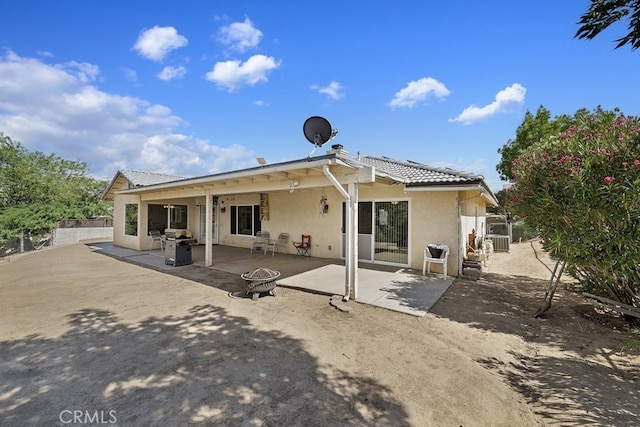 rear view of house with a patio and an outdoor fire pit