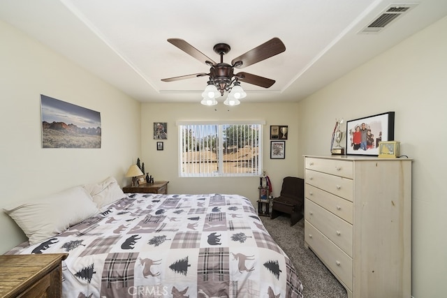 carpeted bedroom featuring a tray ceiling and ceiling fan