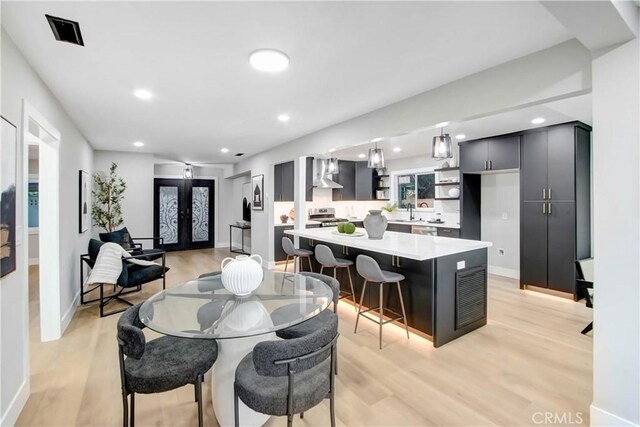 dining space featuring french doors, sink, and light hardwood / wood-style flooring