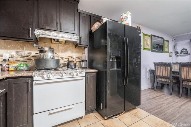 kitchen featuring black refrigerator with ice dispenser, dark brown cabinetry, white range with gas stovetop, light hardwood / wood-style floors, and tasteful backsplash