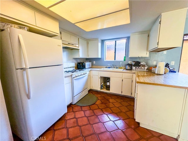 kitchen with white appliances, white cabinetry, and sink