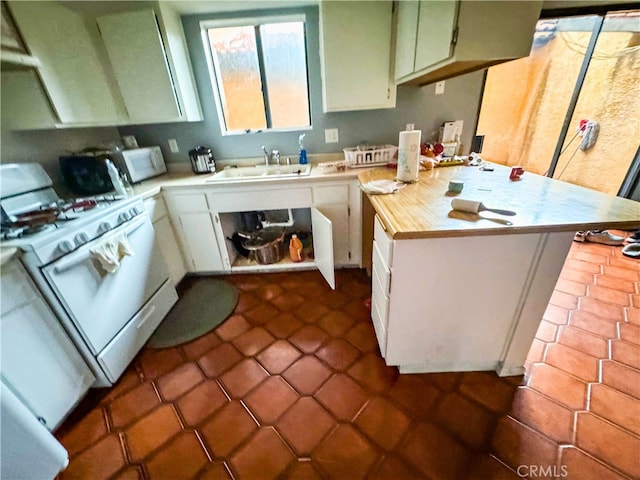 kitchen with white gas range oven, sink, and white cabinets