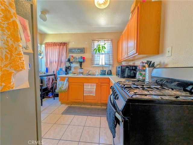 kitchen featuring a textured ceiling, sink, range with gas cooktop, and light tile patterned flooring