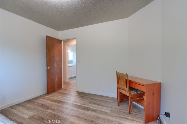 office area featuring a textured ceiling, baseboards, and wood finished floors