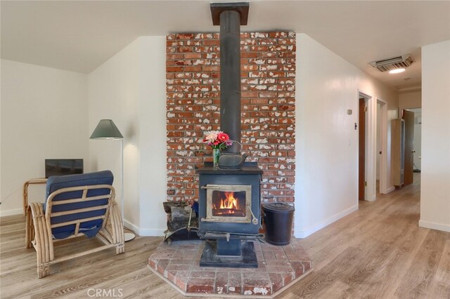 living room featuring baseboards, wood finished floors, and a wood stove