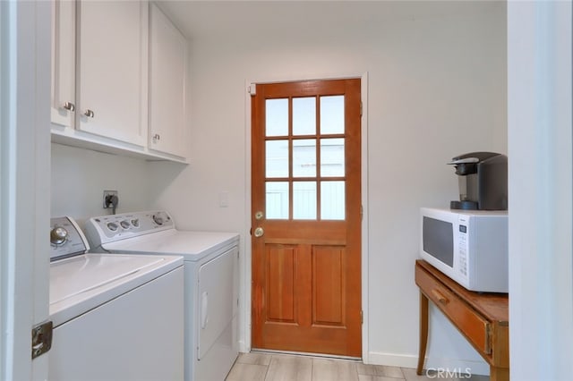 clothes washing area with separate washer and dryer, cabinets, and light wood-type flooring