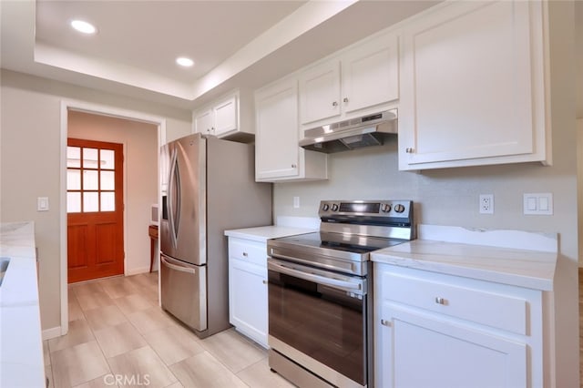 kitchen with white cabinets, appliances with stainless steel finishes, and a tray ceiling