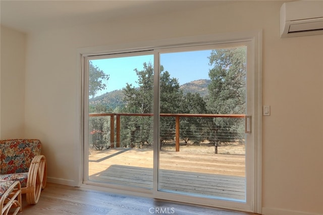 entryway featuring baseboards, a wall unit AC, wood finished floors, and a mountain view