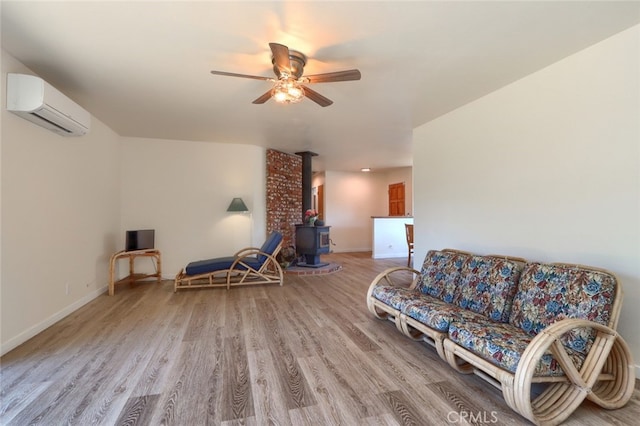 living area featuring a wood stove, wood-type flooring, ceiling fan, and a wall mounted air conditioner