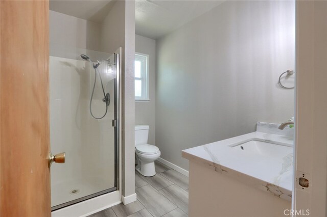 full bath featuring baseboards, toilet, a stall shower, and vanity
