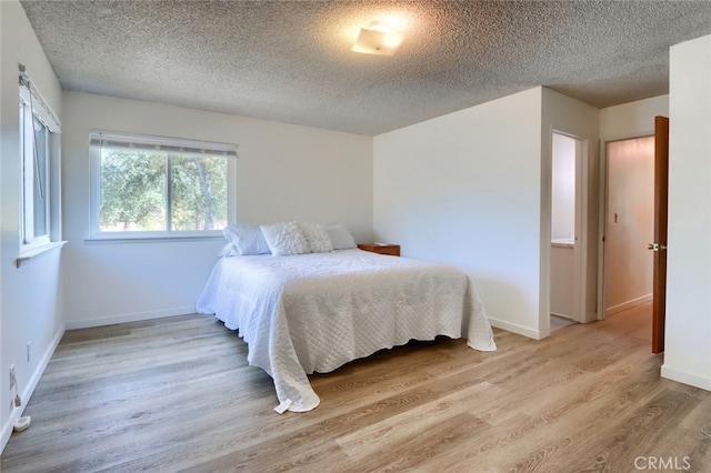 bedroom with light hardwood / wood-style floors and a textured ceiling