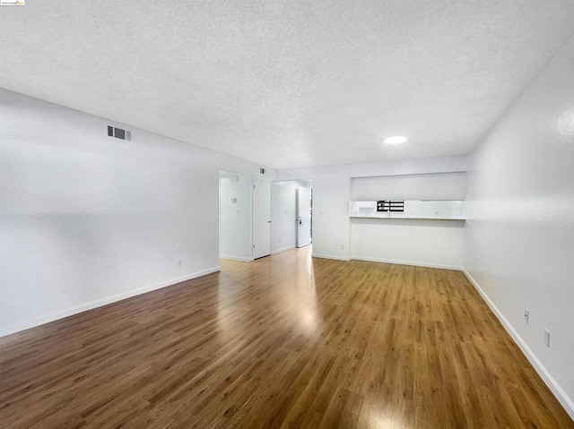 unfurnished living room with wood-type flooring and a textured ceiling