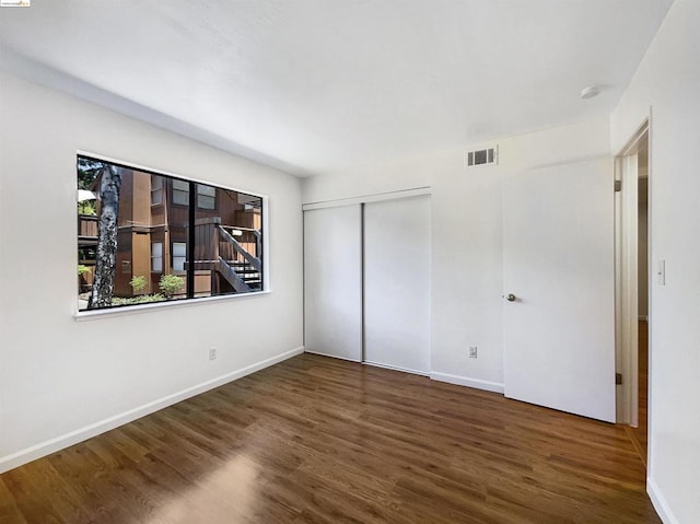 unfurnished bedroom featuring dark wood-type flooring and a closet