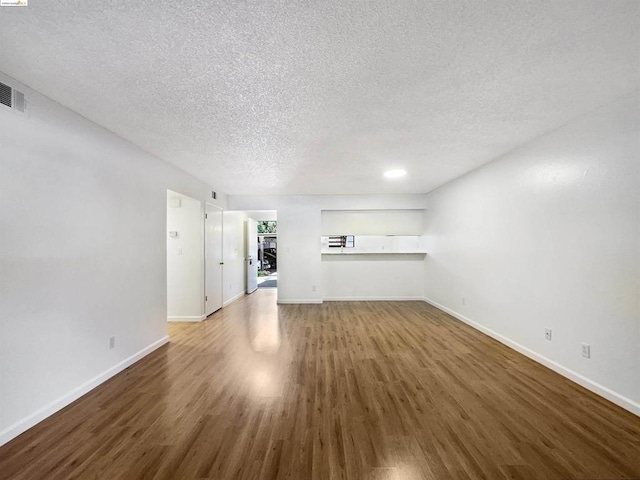 unfurnished living room featuring dark hardwood / wood-style flooring and a textured ceiling