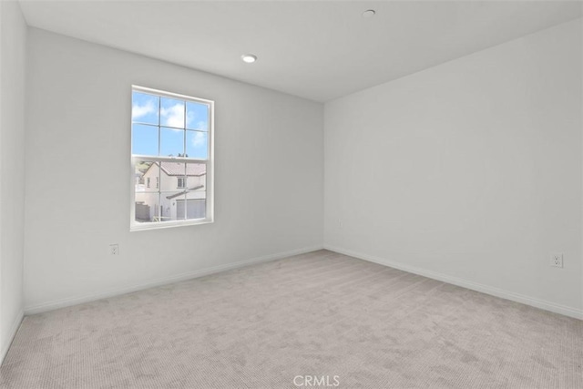 empty room featuring baseboards and light colored carpet