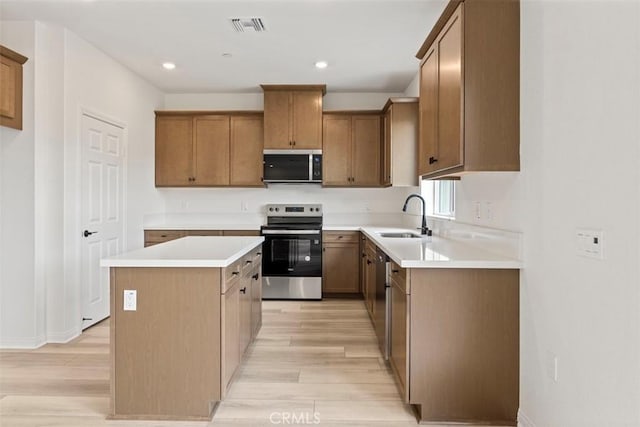 kitchen featuring a kitchen island, appliances with stainless steel finishes, sink, and light hardwood / wood-style flooring