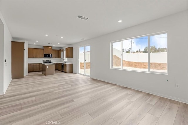 unfurnished living room with sink and light hardwood / wood-style flooring