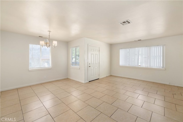 empty room featuring a notable chandelier and light tile patterned floors