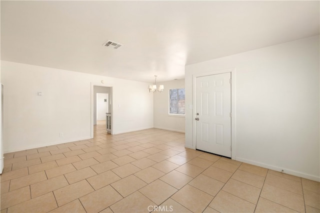 tiled spare room featuring an inviting chandelier