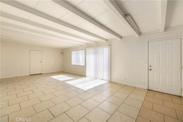 tiled spare room featuring beamed ceiling