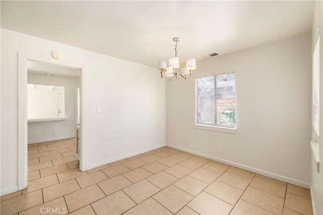 spare room featuring a notable chandelier and light tile patterned floors