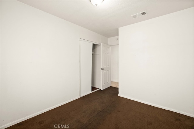 unfurnished bedroom featuring dark colored carpet and a closet