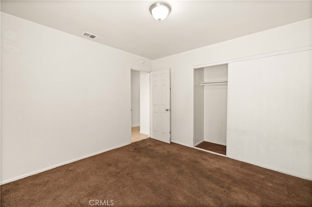 unfurnished bedroom with dark colored carpet and a closet